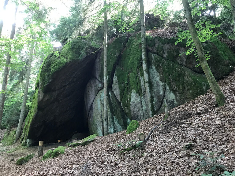 Ein grosser Felsblock neben einem Waldweg mit Bäumen - Diebstein.