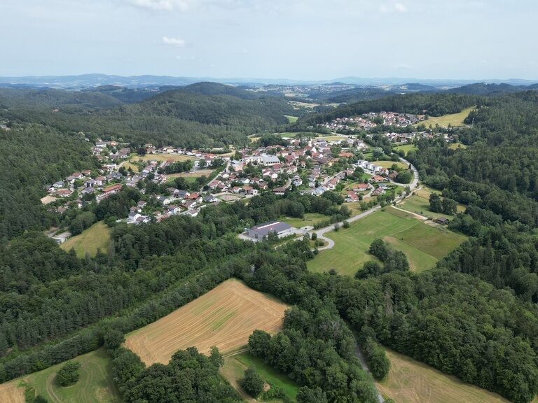 Ein idyllisches Dorf in einer natürlichen Landschaft aus der Vogelperspektive.
