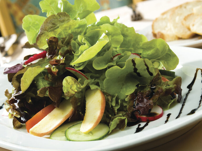 Ein weißer Teller mit frischem Salat in einem stilvollen Restaurant.